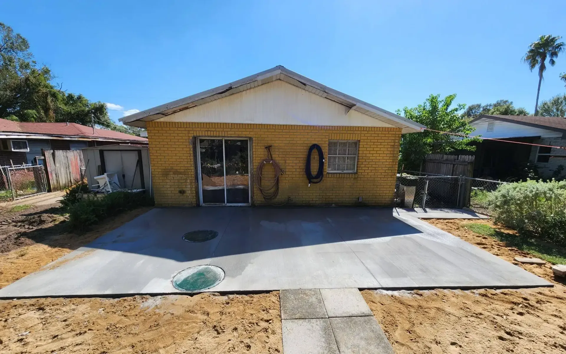 A yellow house with a concrete driveway in front of it.