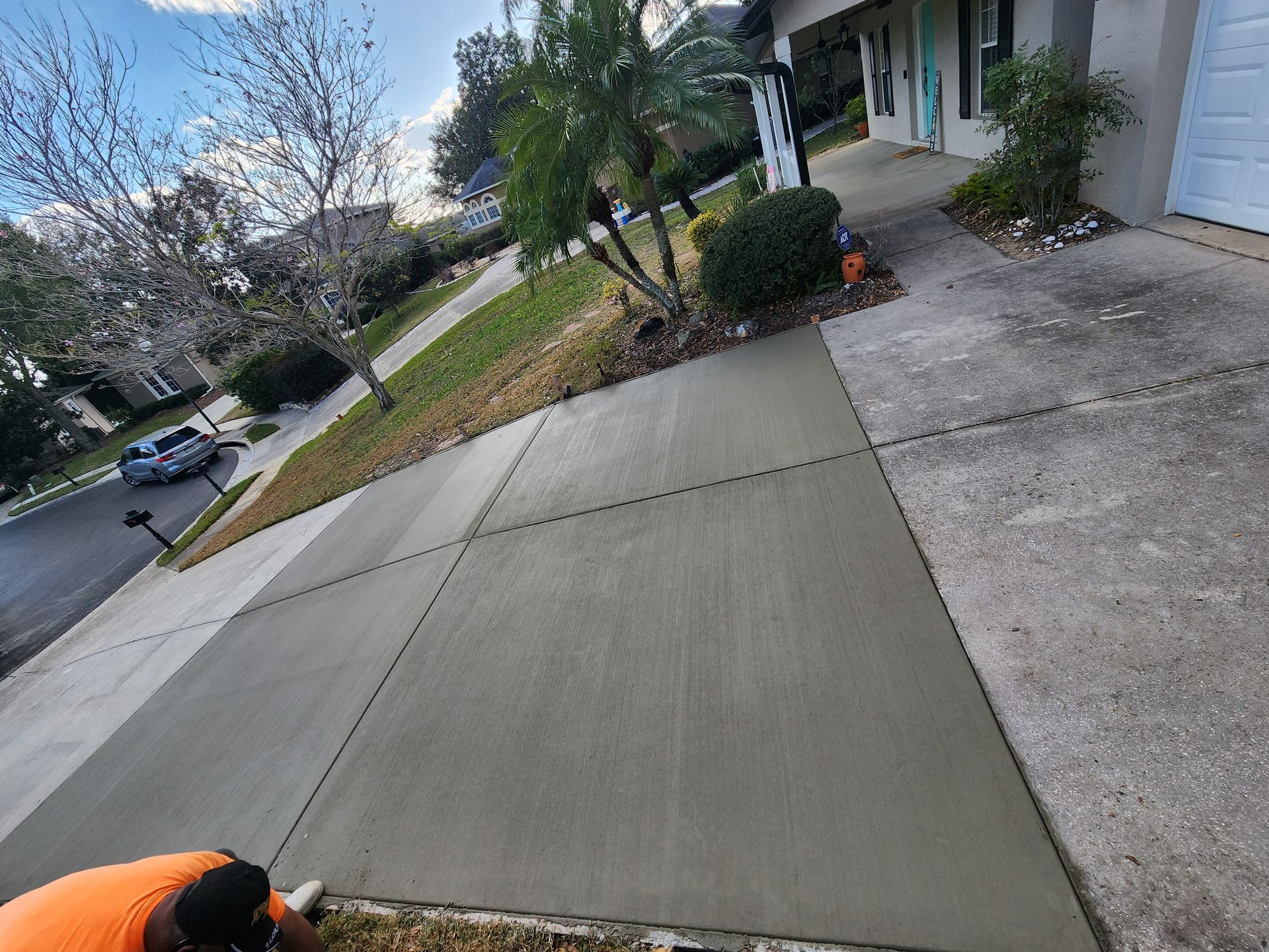 A man is laying concrete on a sidewalk in front of a house.