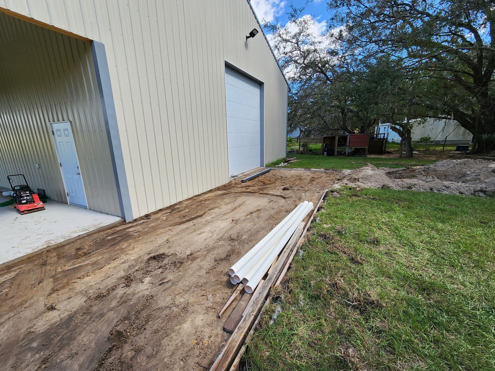 A garage door is open and a lawn mower is parked in front of it.