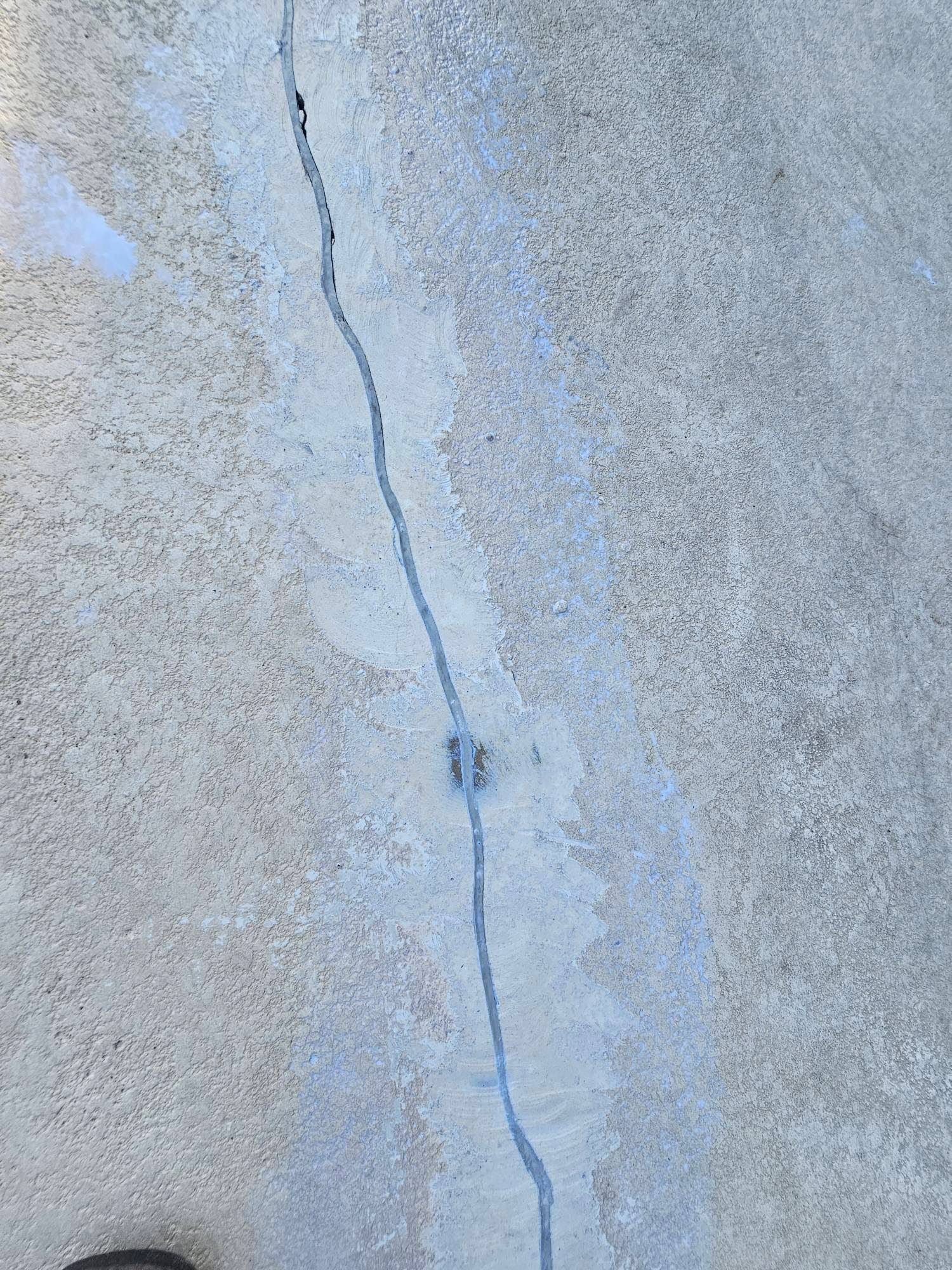 Long crack in a concrete surface; gray color.