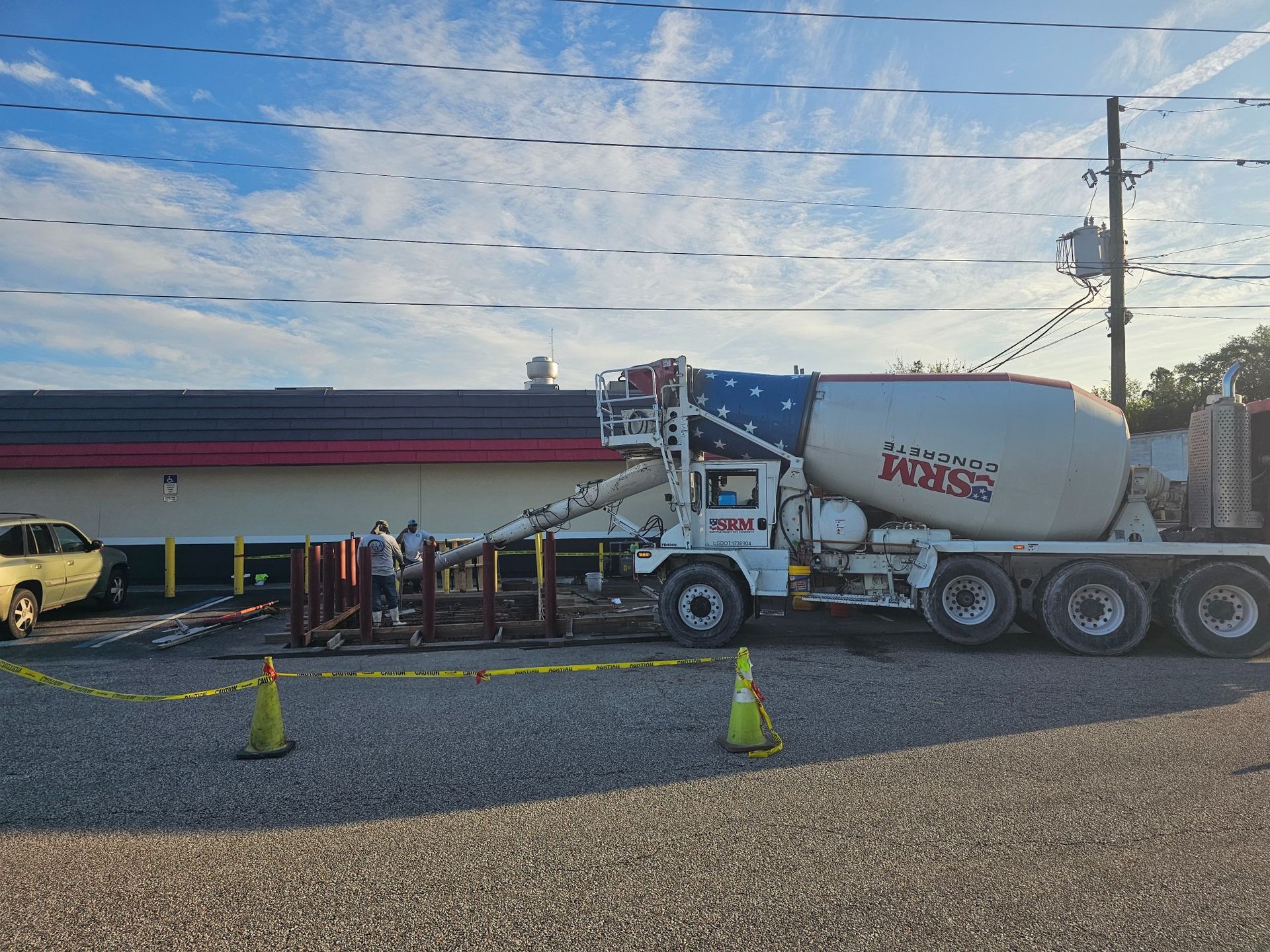 Cement truck pouring concrete next to a building under construction.