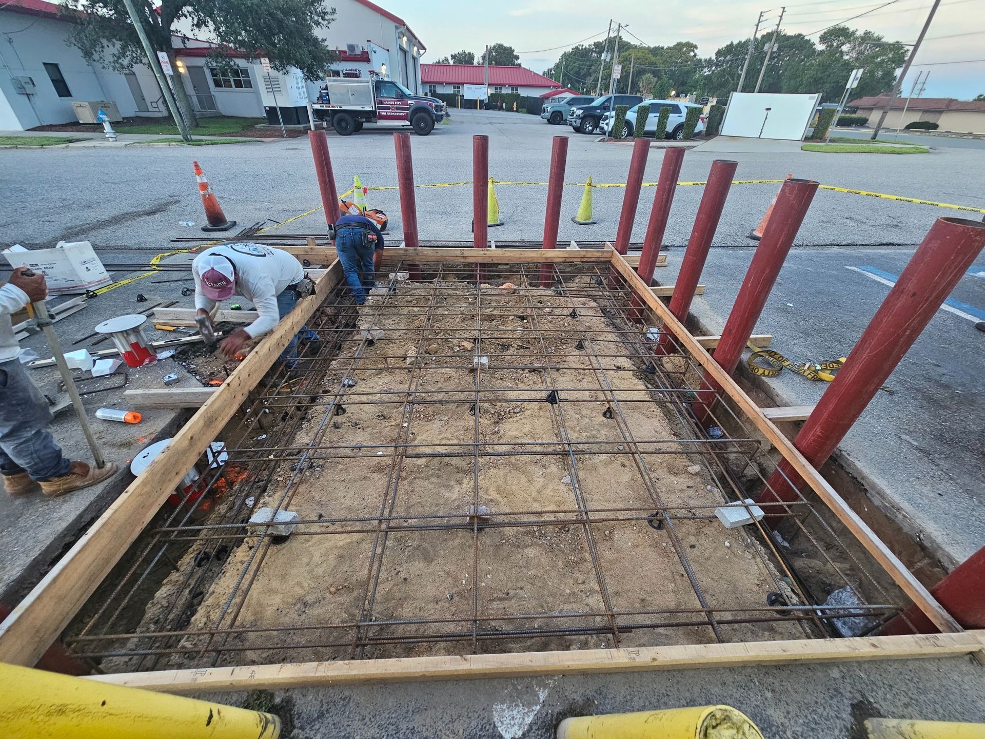 Construction site with workers, preparing a rectangular area with rebar and wooden framing.
