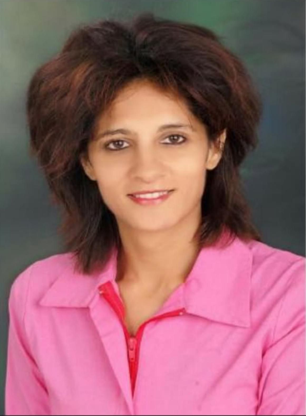 Woman with brown hair in a pink shirt smiling.