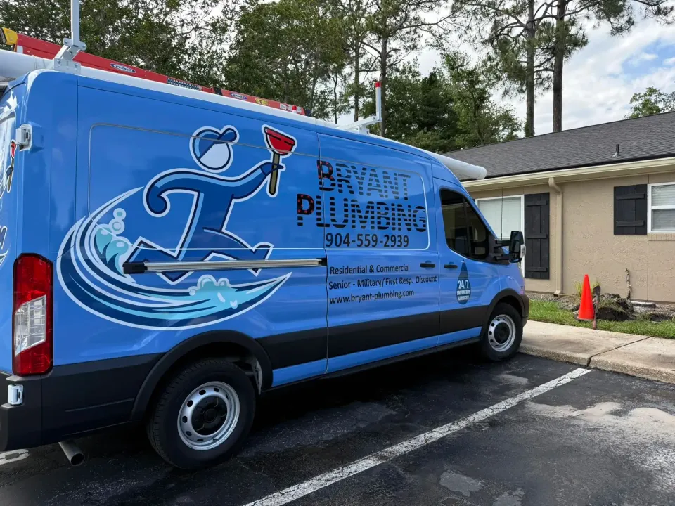 Blue plumbing service van parked outside a building, with company logo and text on the side.