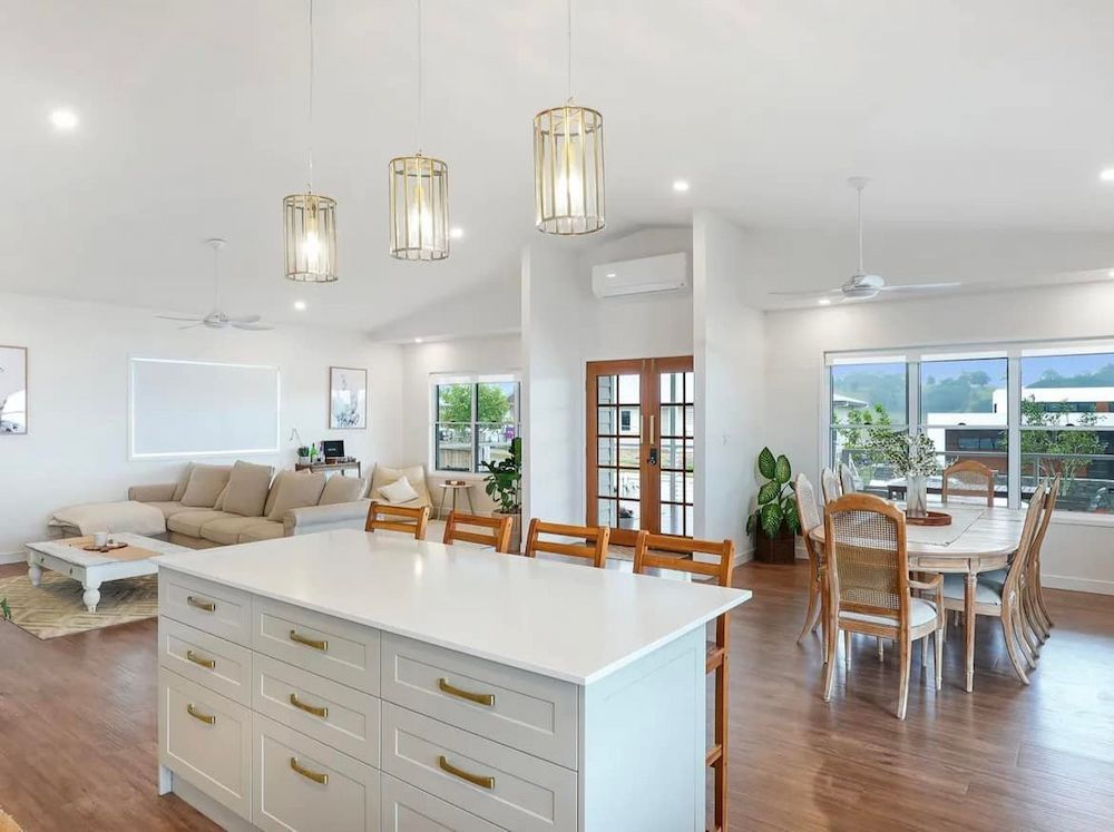 Open-plan Living Space With a White Kitchen Island, Dining Area — JGD Constructions in Lake Eacham, QLD