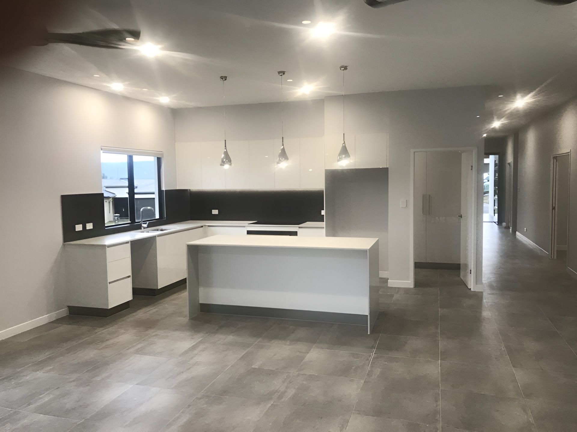 Modern Kitchen With White Cabinetry, Black Backsplash, and a Large Island — JGD Constructions in Lake Eacham, QLD