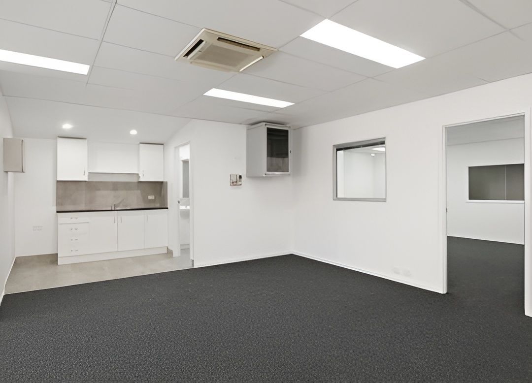 Empty Office Space With White Walls, Gray Carpet, and a Small Kitchenette — JGD Constructions in Lake Eacham, QLD