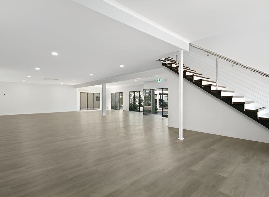 Empty Commercial Space With Gray Wood-look Flooring, White Walls, and a Staircase — JGD Constructions in Lake Eacham, QLD