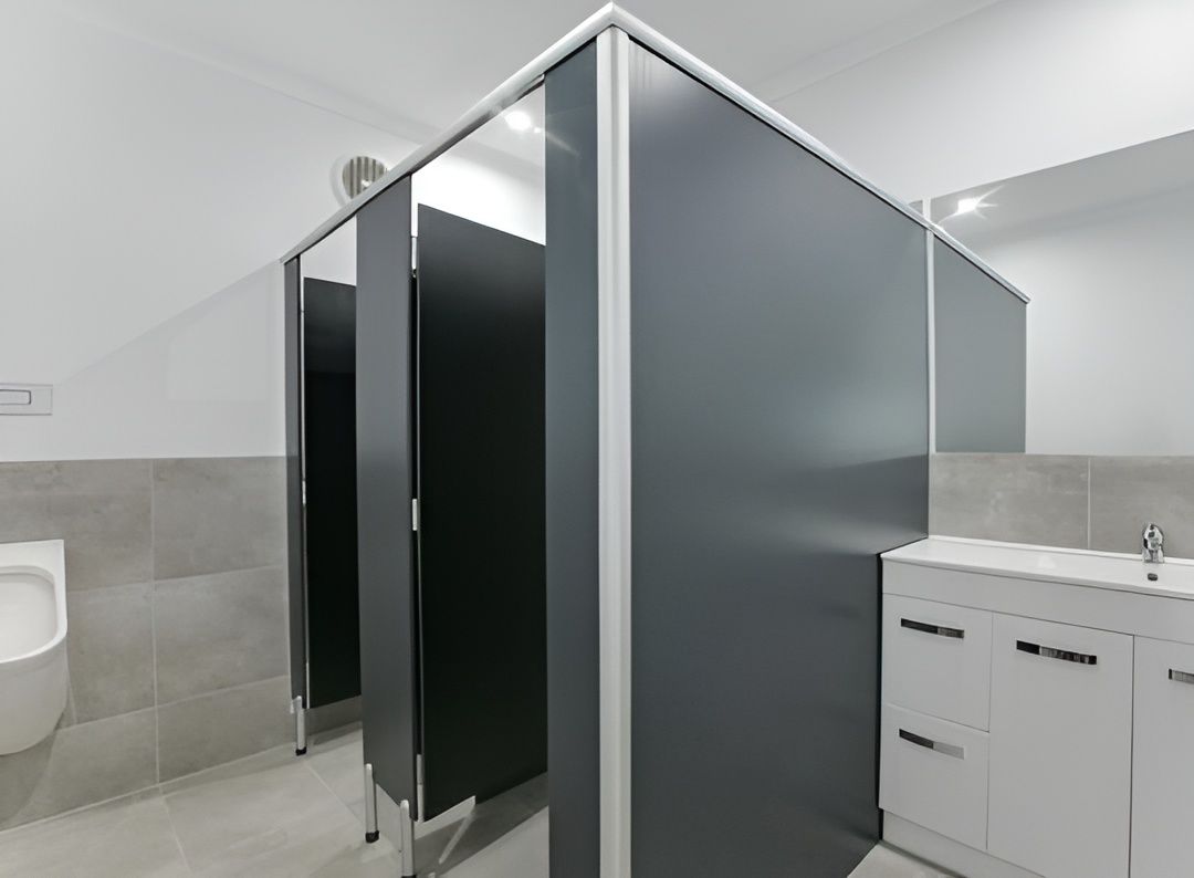 Public Restroom With Gray Stalls, a White Sink Cabinet, and a Urinal — JGD Constructions in Lake Eacham, QLD