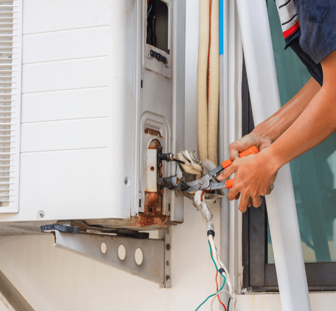Person using pliers to repair an outdoor air conditioning unit.
