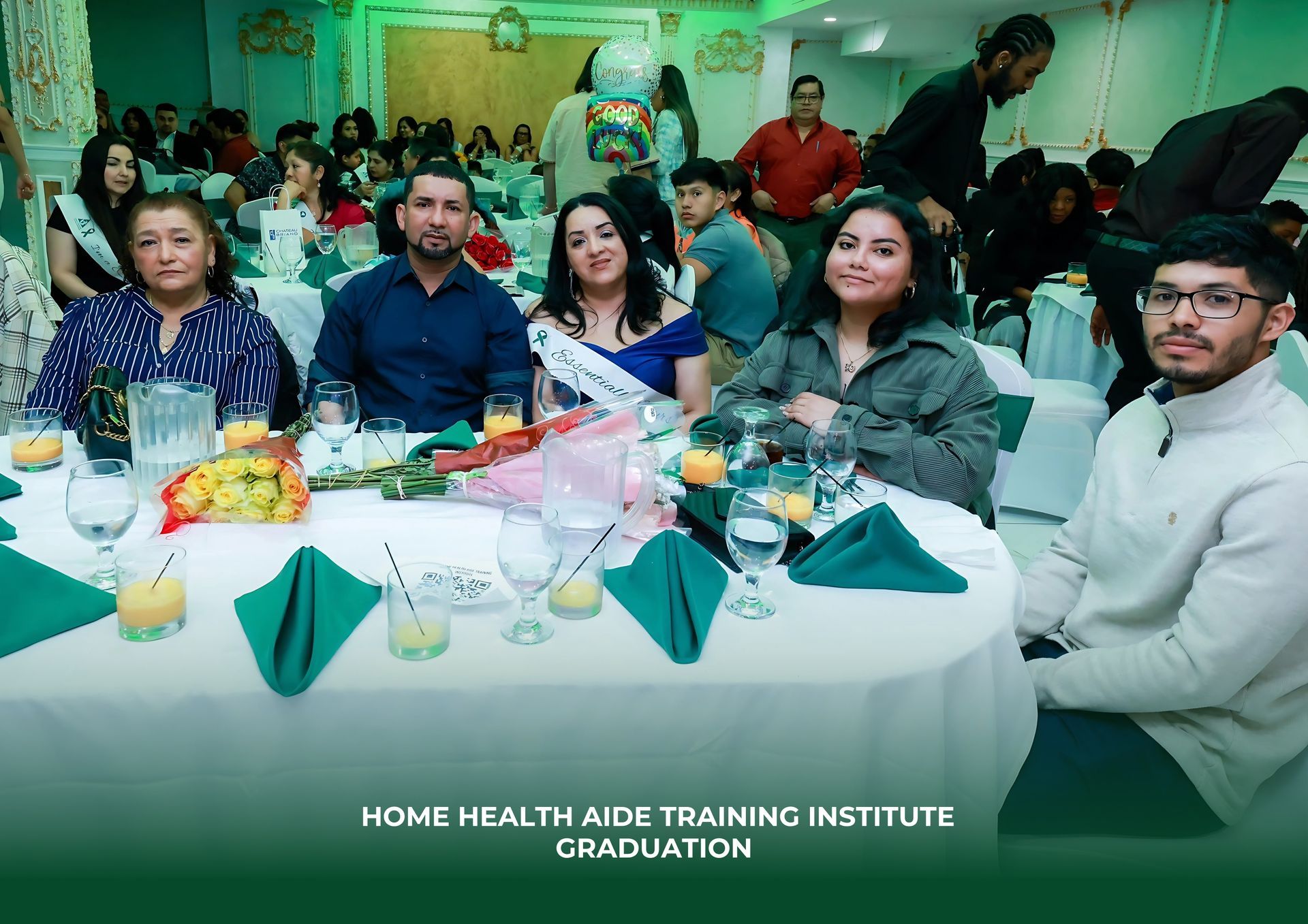 A group of people are sitting at a table at a home health aide training institute graduation.