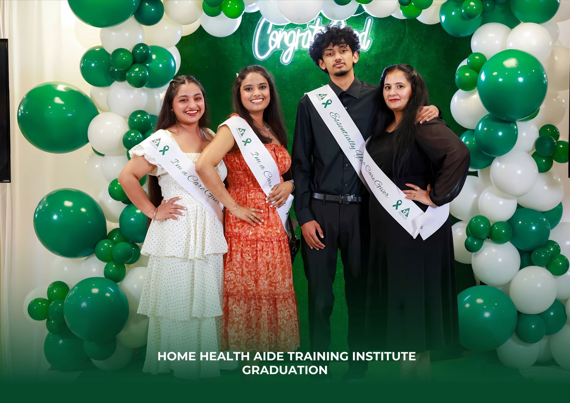 A group of people are posing for a picture in front of green balloons.