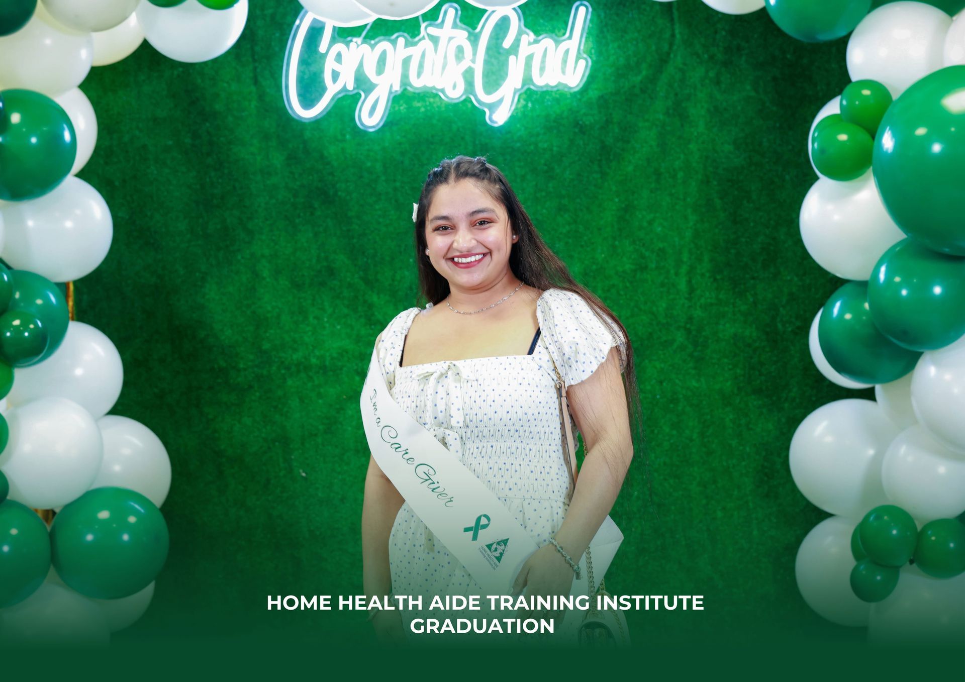 A woman is standing in front of a green and white balloon arch.
