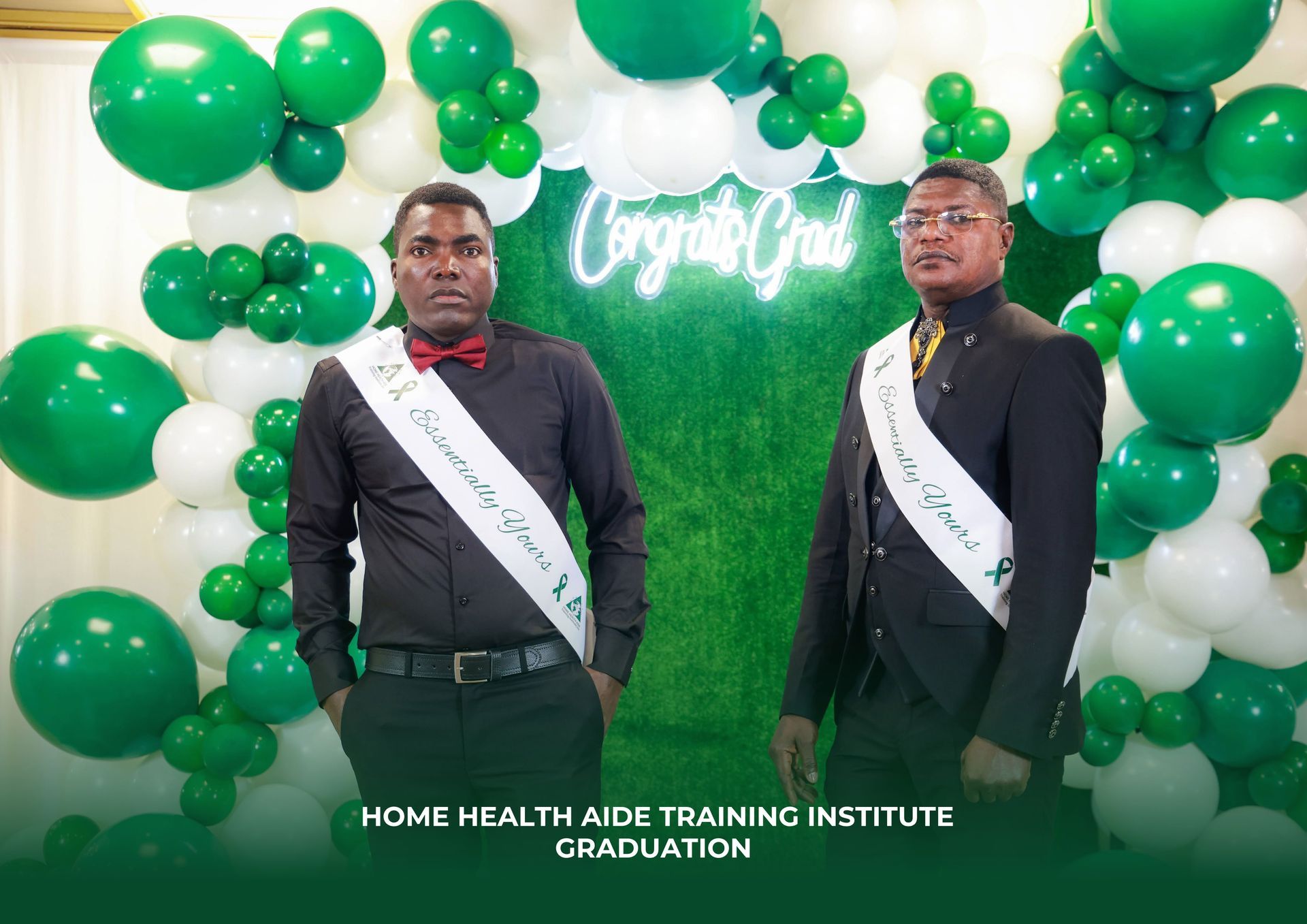 Two men are standing in front of a wall of green and white balloons.