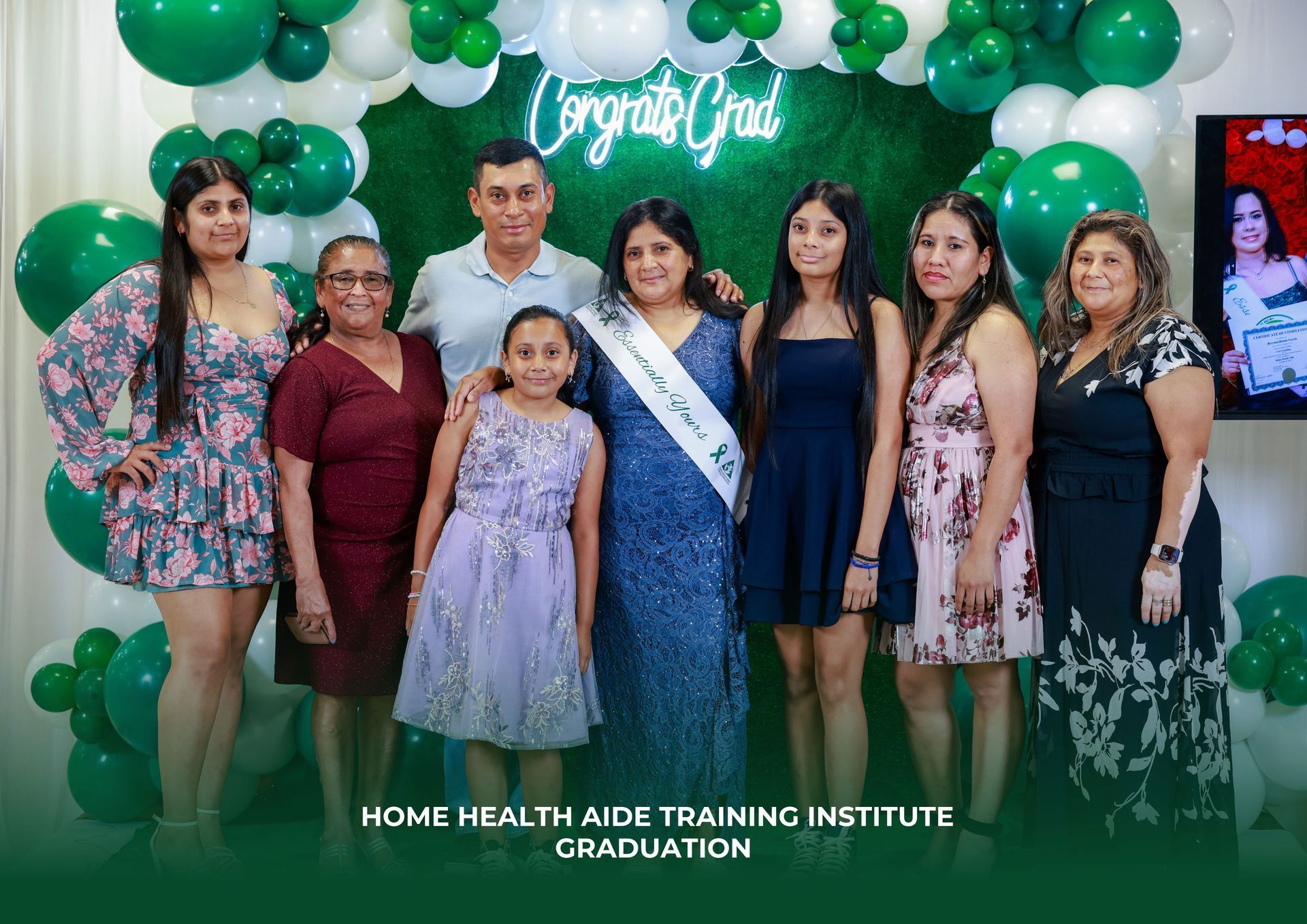A group of people are posing for a picture in front of green and white balloons.