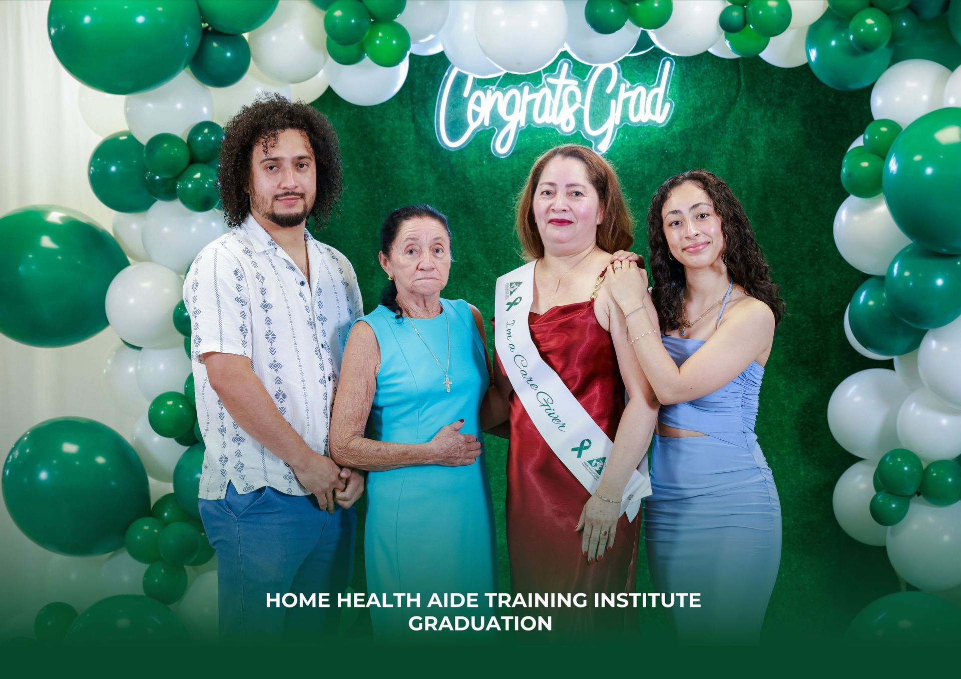 People are posing for a picture in front of a wall of green and white balloons.