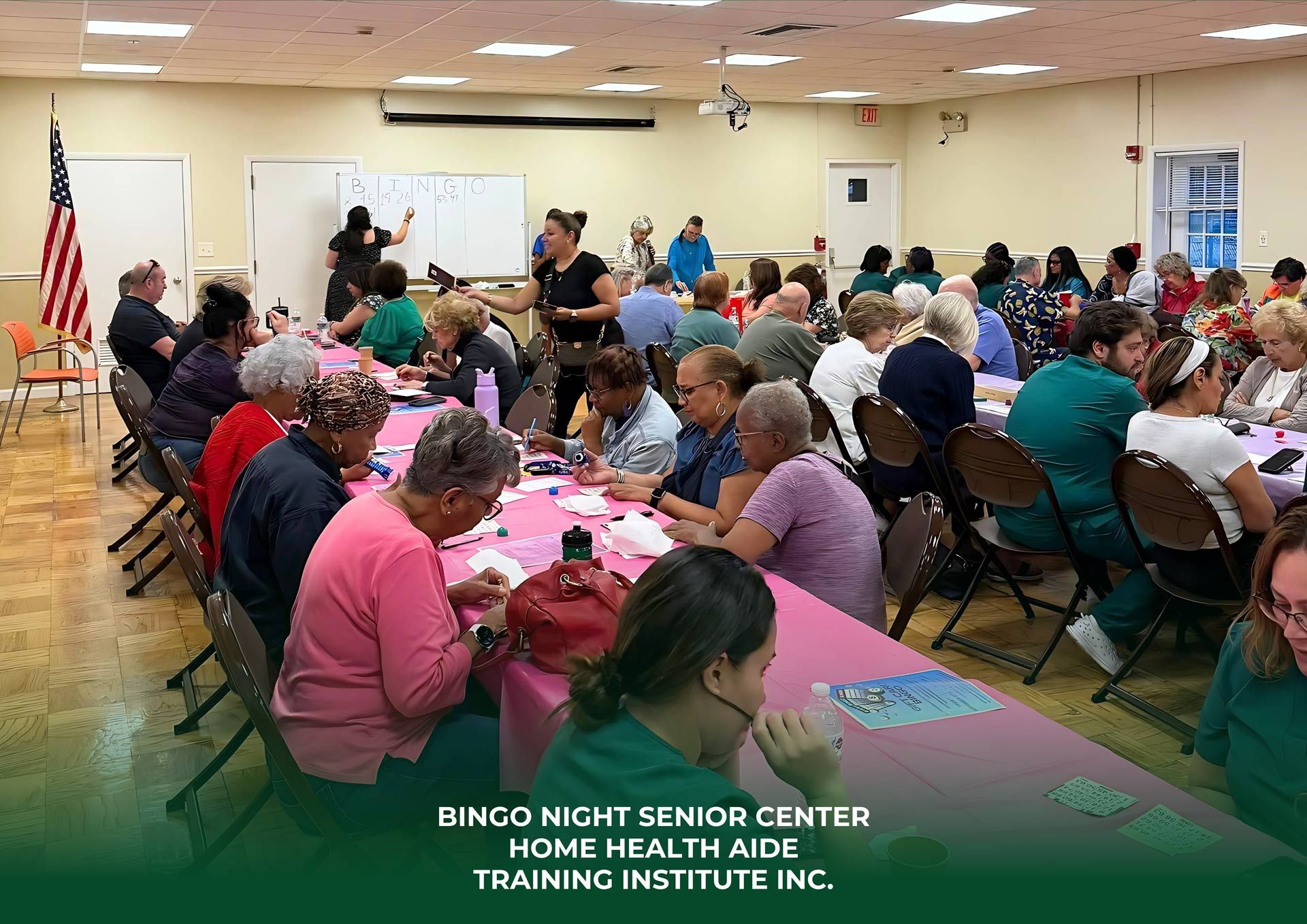Seniors at tables in a community center participate in an activity, with instructors at the front, American flag visible.