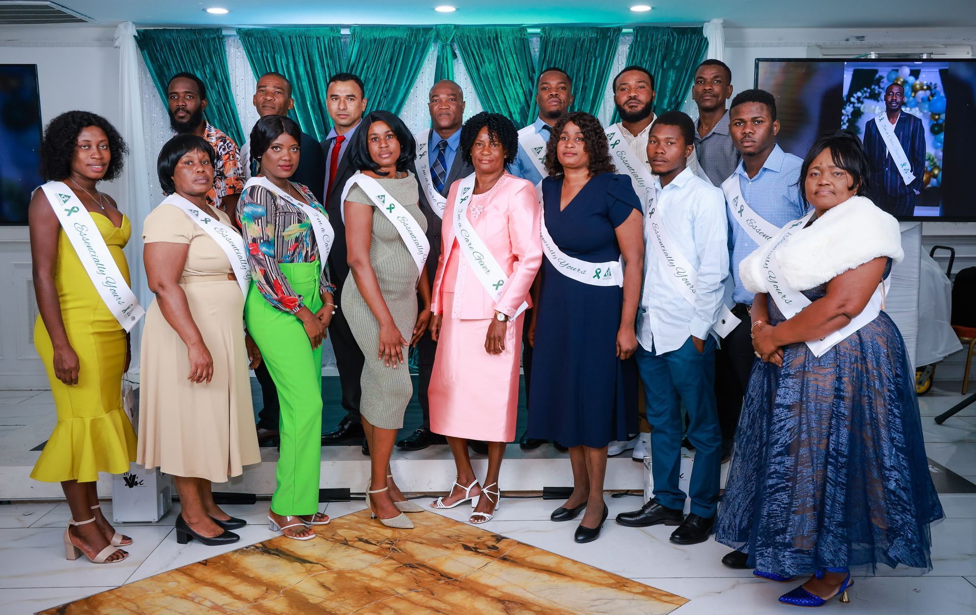 A group of women in scrubs is standing around a table with food and a cake.