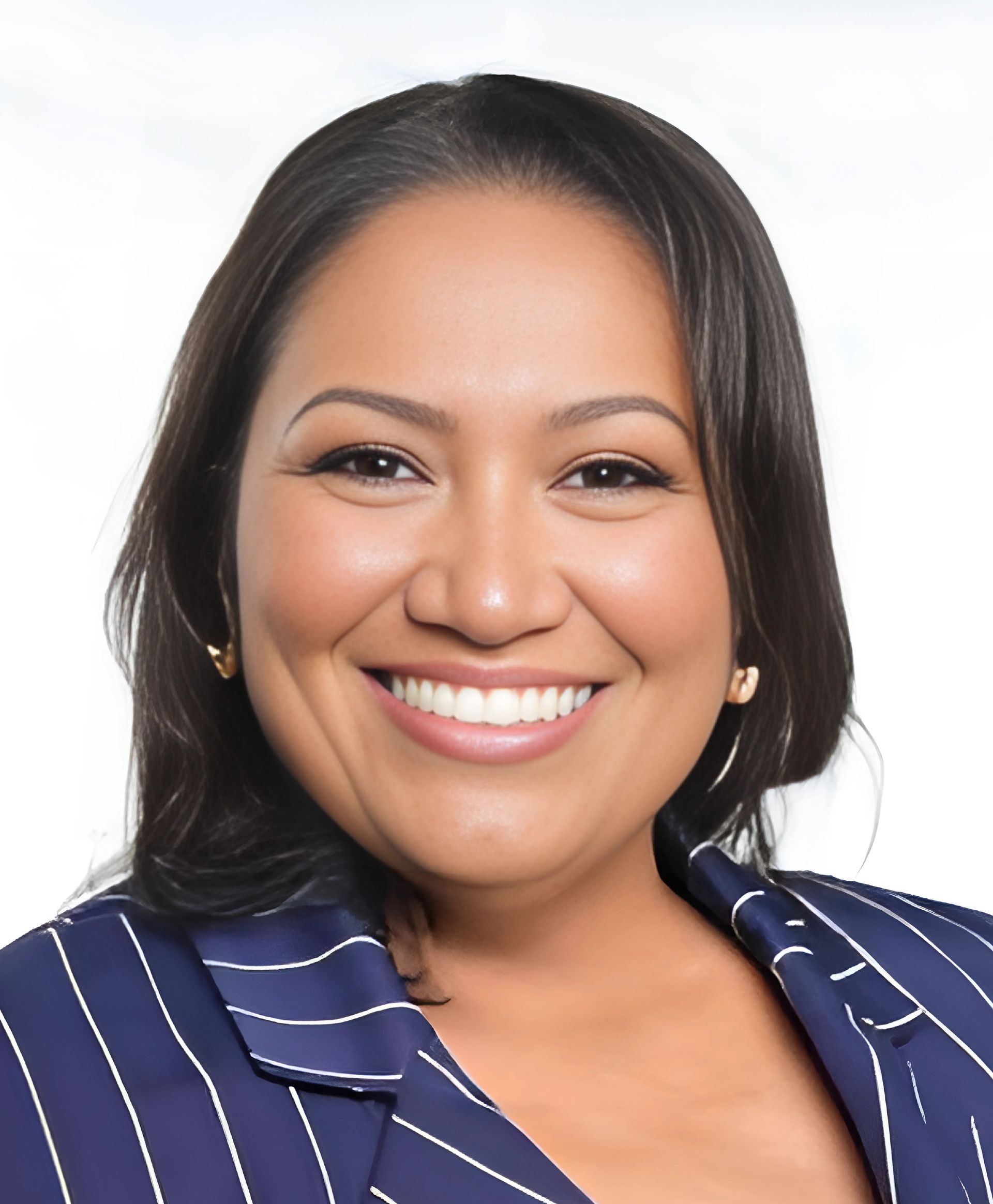Woman smiling, wearing a blue striped blazer, with dark hair and gold earrings, against a white background.