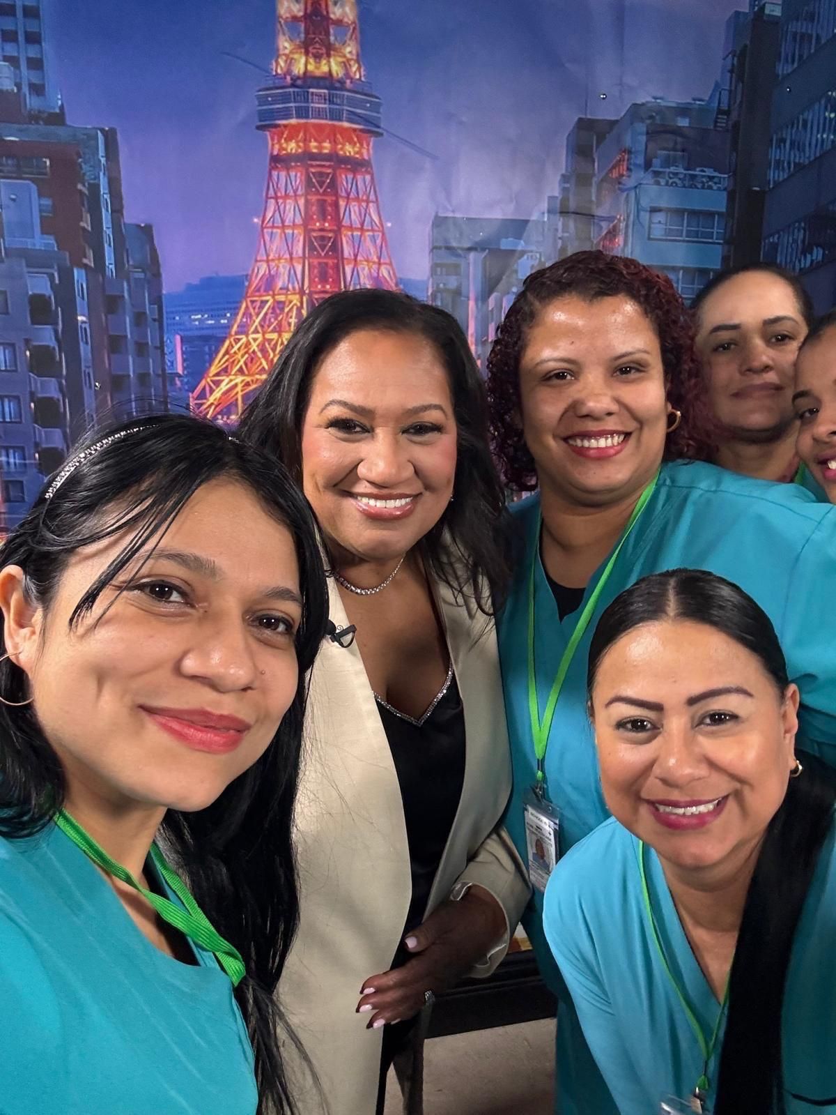 A woman in a black dress and cape is smiling.