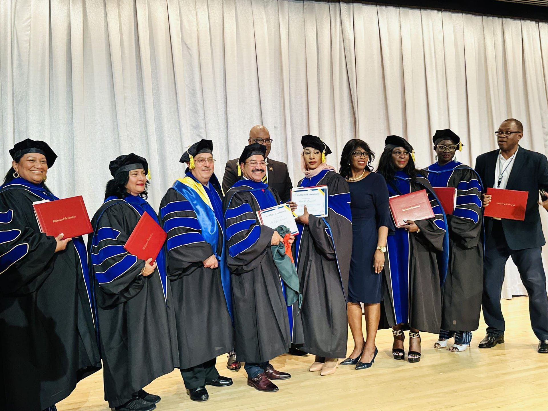 A group of graduates are posing for a picture on a stage.