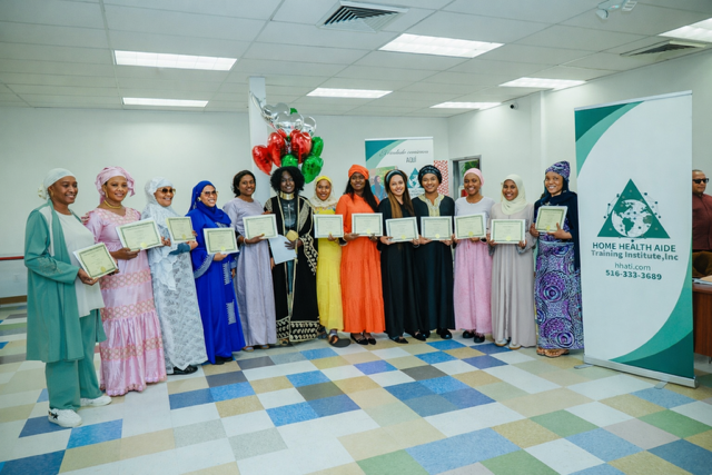 A group of people wearing headscarves hold awards while standing in a room with a large branded sign in the background.