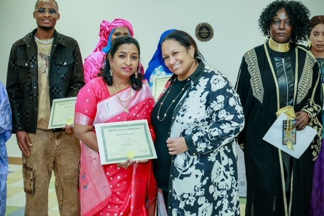A group of people holding certificates, with two central figures smiling as they pose for a photo at an indoor event.