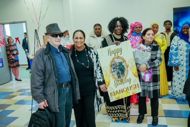 A group of people standing together in a room, with one individual holding a 