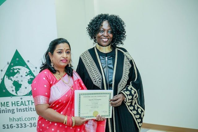 Two people stand side-by-side, one presenting a certificate to the other in front of a branded banner.
