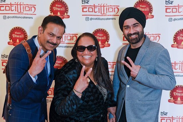 Three smiling people in formal wear pose for a photo with 