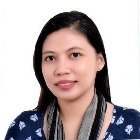 A headshot of a person with long dark hair, wearing a patterned blue top and a gray scarf against a white background.