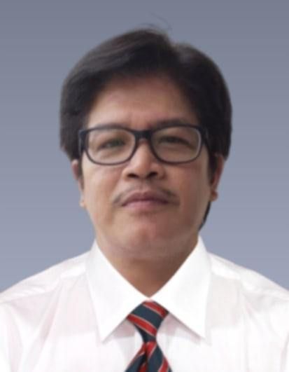 Headshot of a person wearing black-rimmed glasses, a white collared shirt, and a striped tie against a gray background.