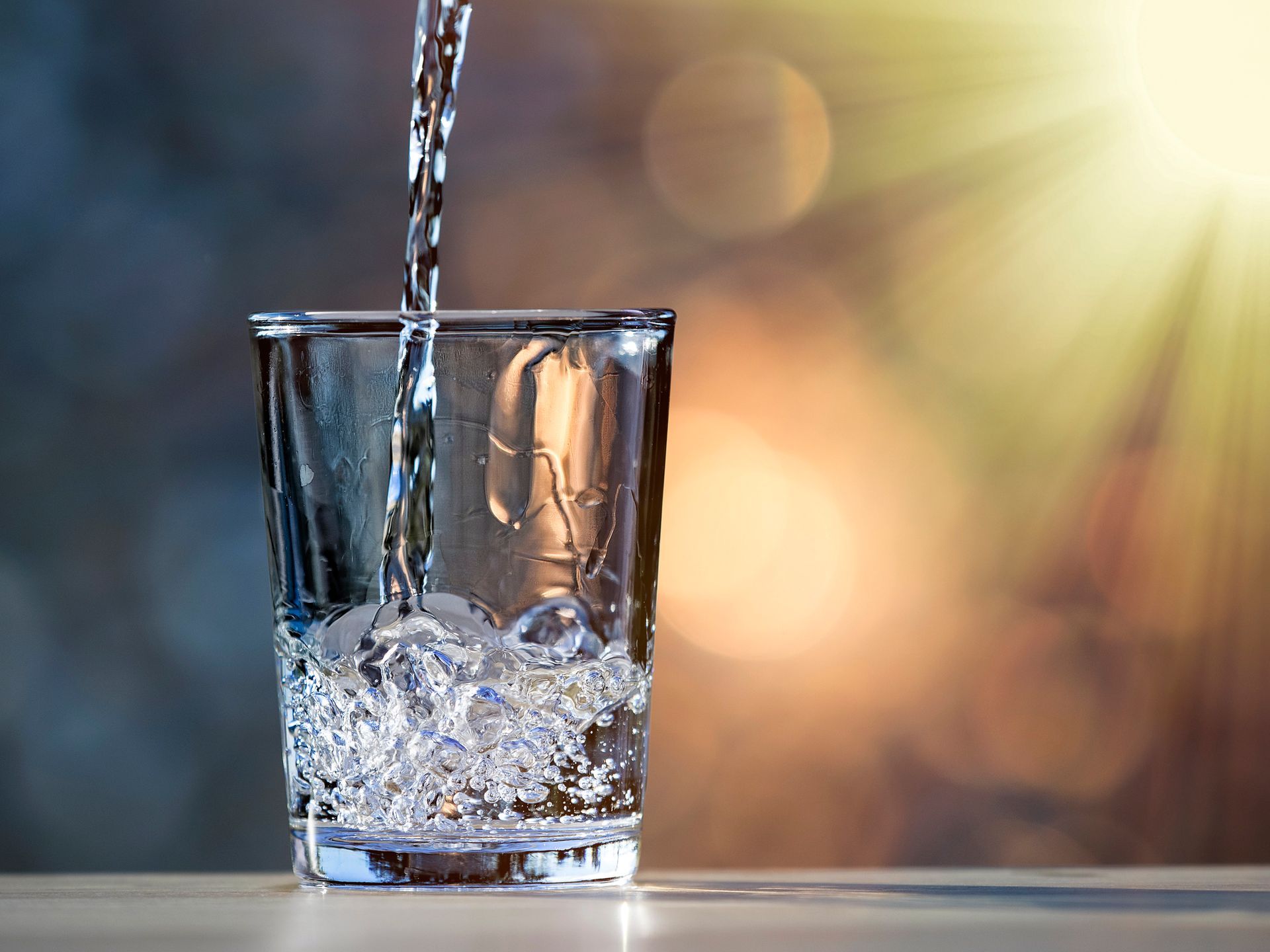 Water is being poured into a glass on a table.