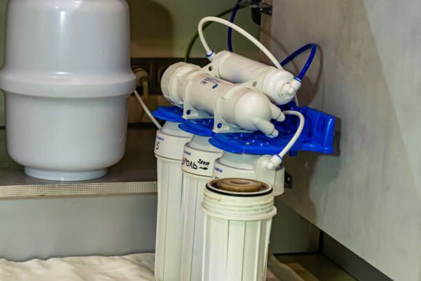 A water filter is sitting under a sink in a kitchen.
