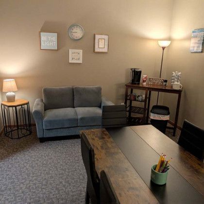Cozy office with a couch, table with coffee station, and decorative wall art.