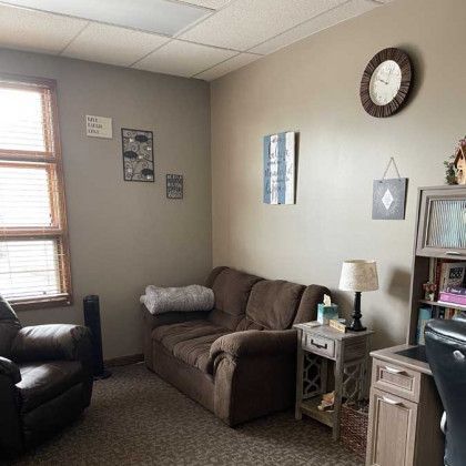 Cozy counseling office with a brown sofa, armchair, and desk.