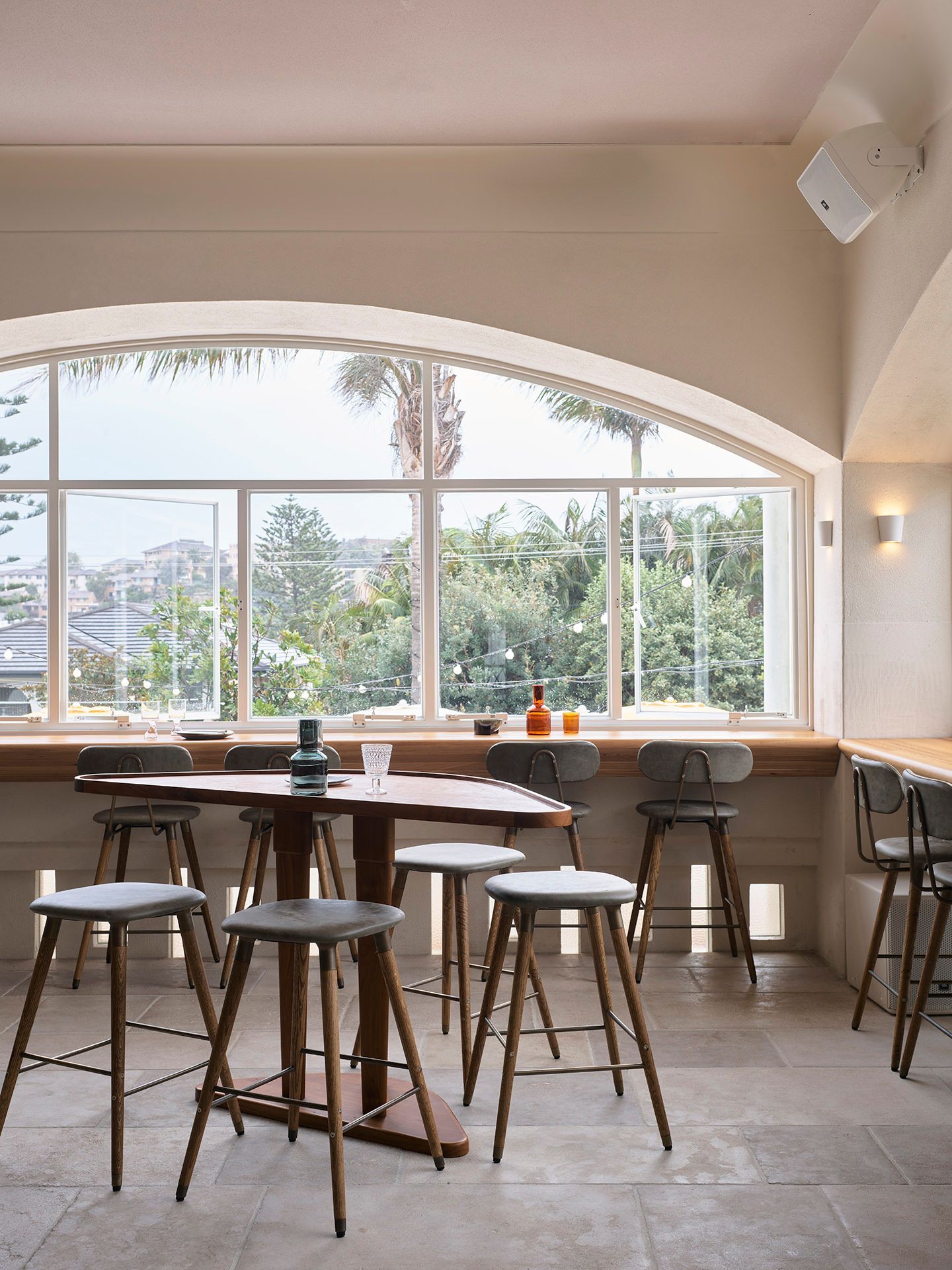 A restaurant with tables and stools in front of a large window.