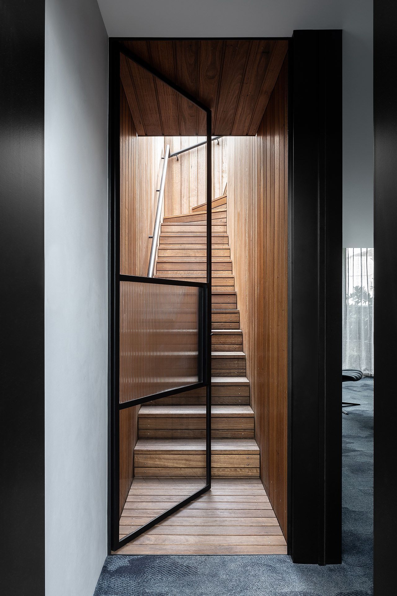 A wooden staircase with a glass door leading to the second floor.