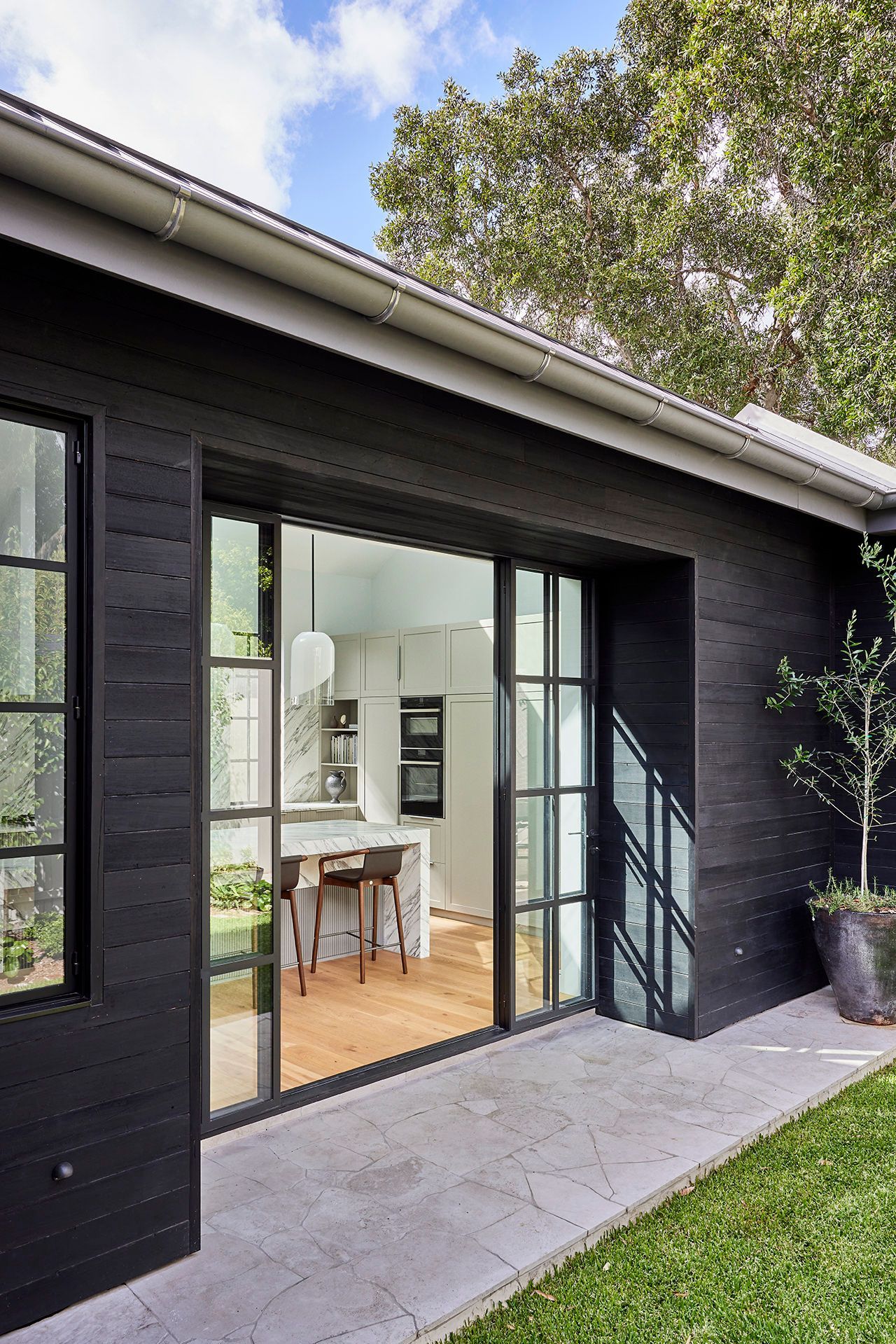 A black house with sliding glass doors leading to a kitchen.