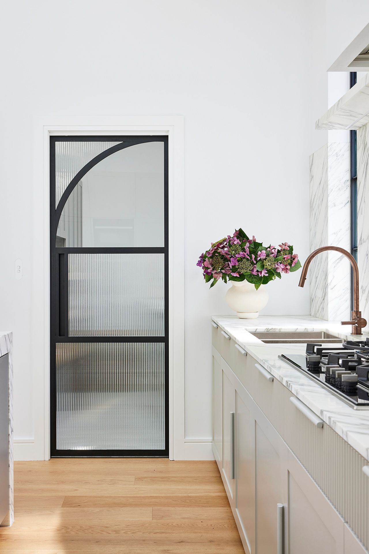 There is a vase of flowers on the counter in the kitchen.