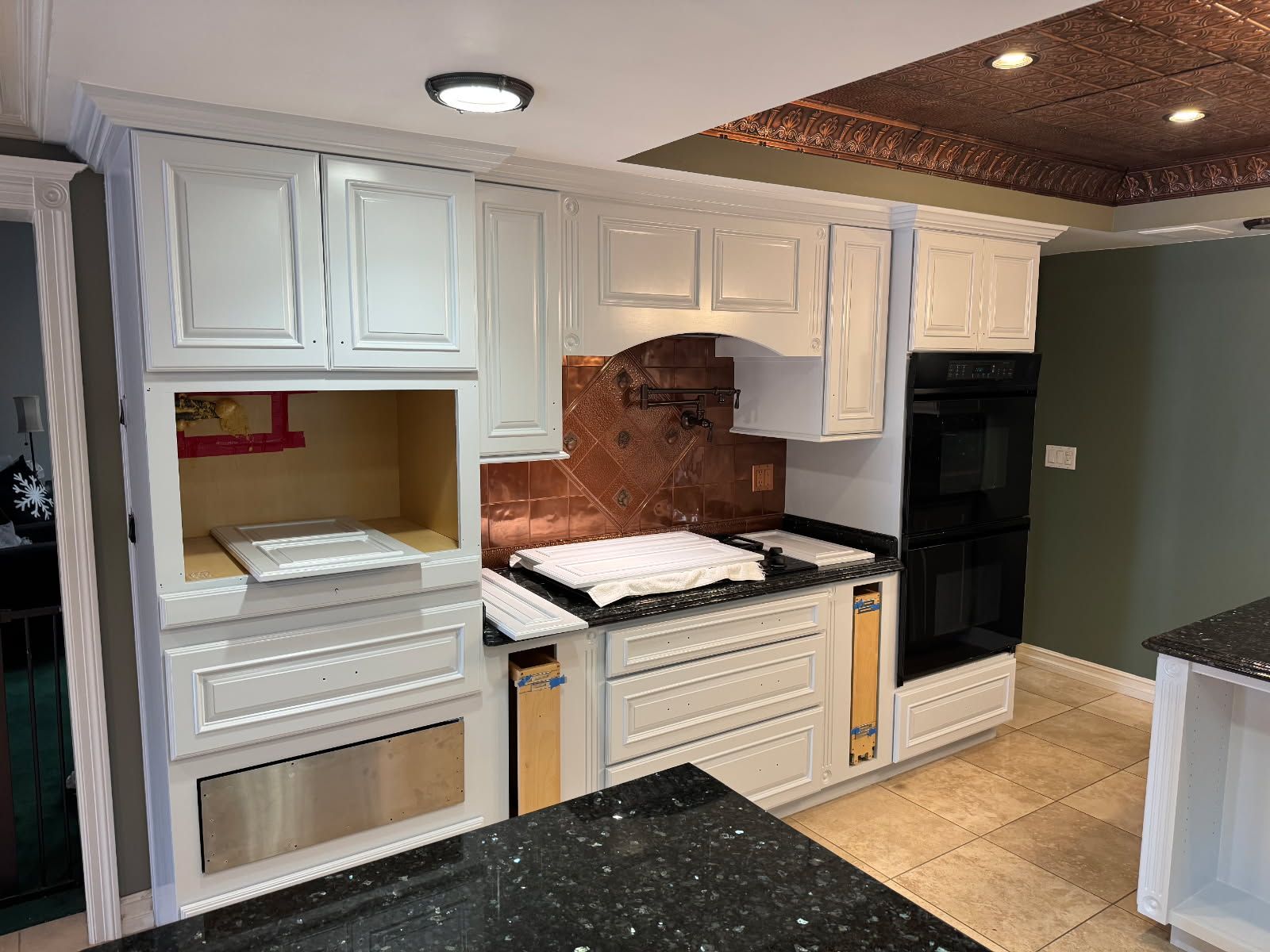 A kitchen with white cabinets, black countertops, and stainless steel appliances after painting - Long Beach, CA - Negrini Painting