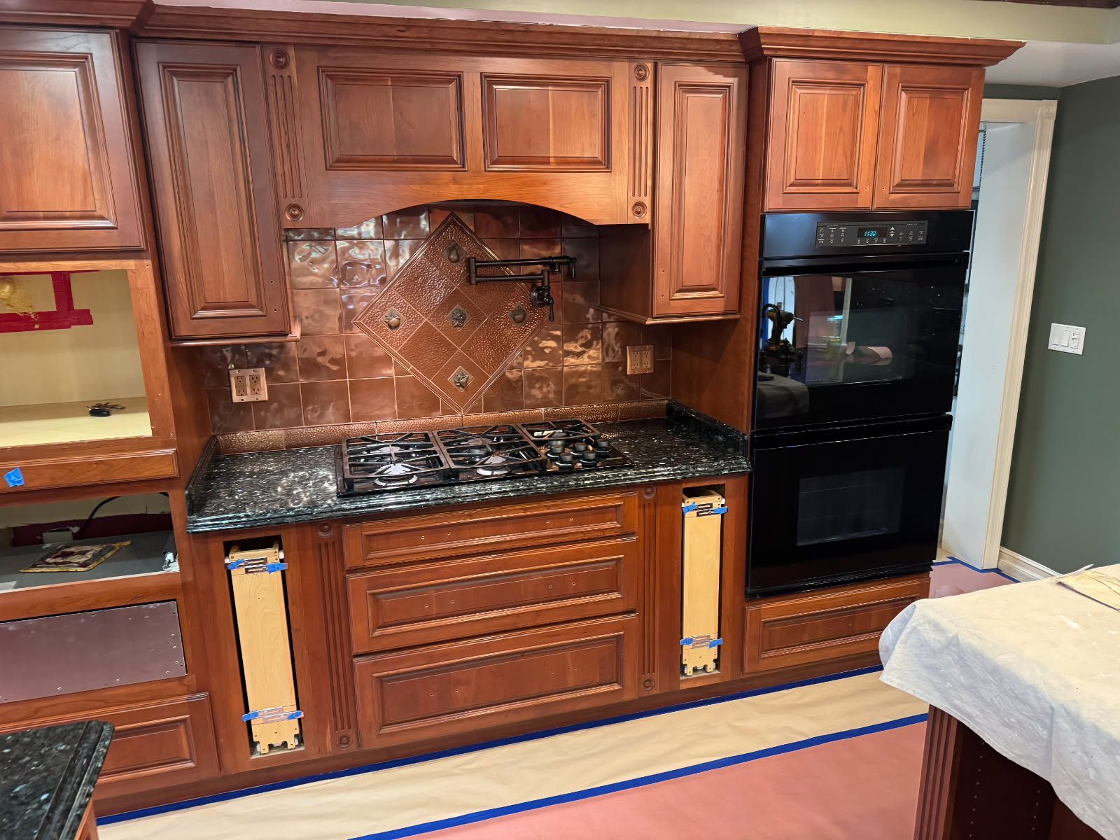 A kitchen with wooden cabinets and a stove top oven before painting - Long Beach, CA - Negrini Painting