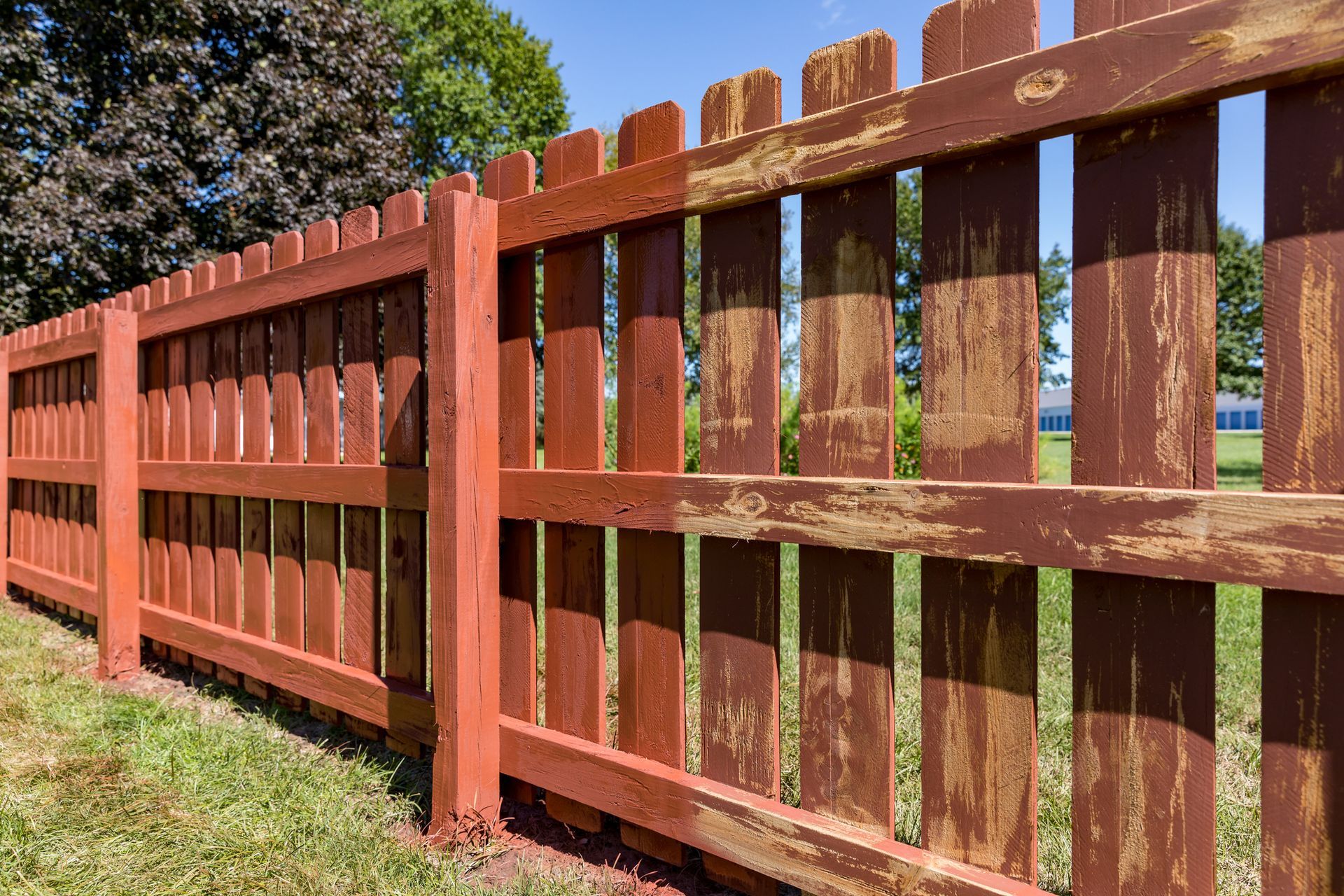 A person is painting a wooden fence with a brush.