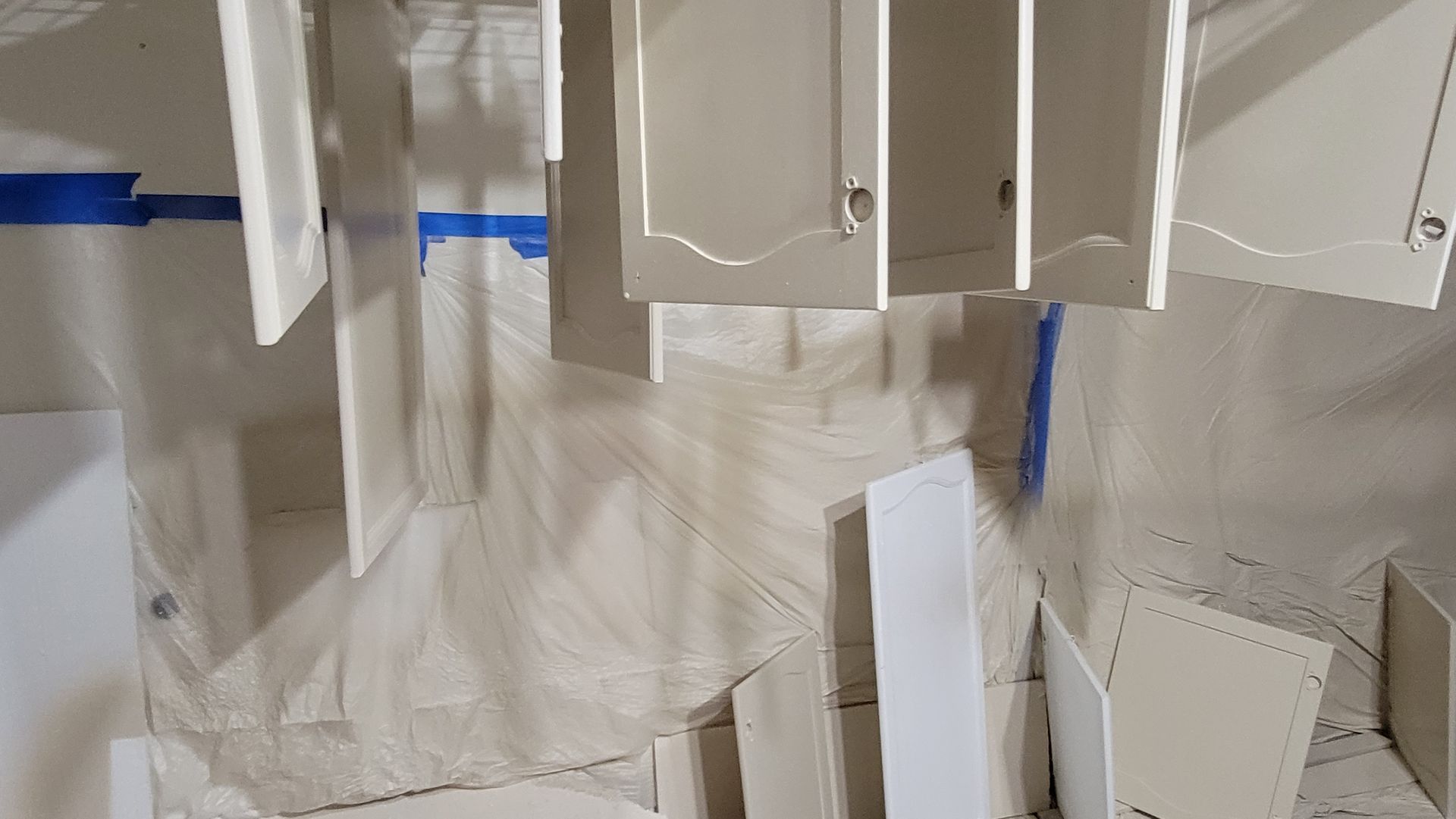 A room filled with white cabinets that are being painted.