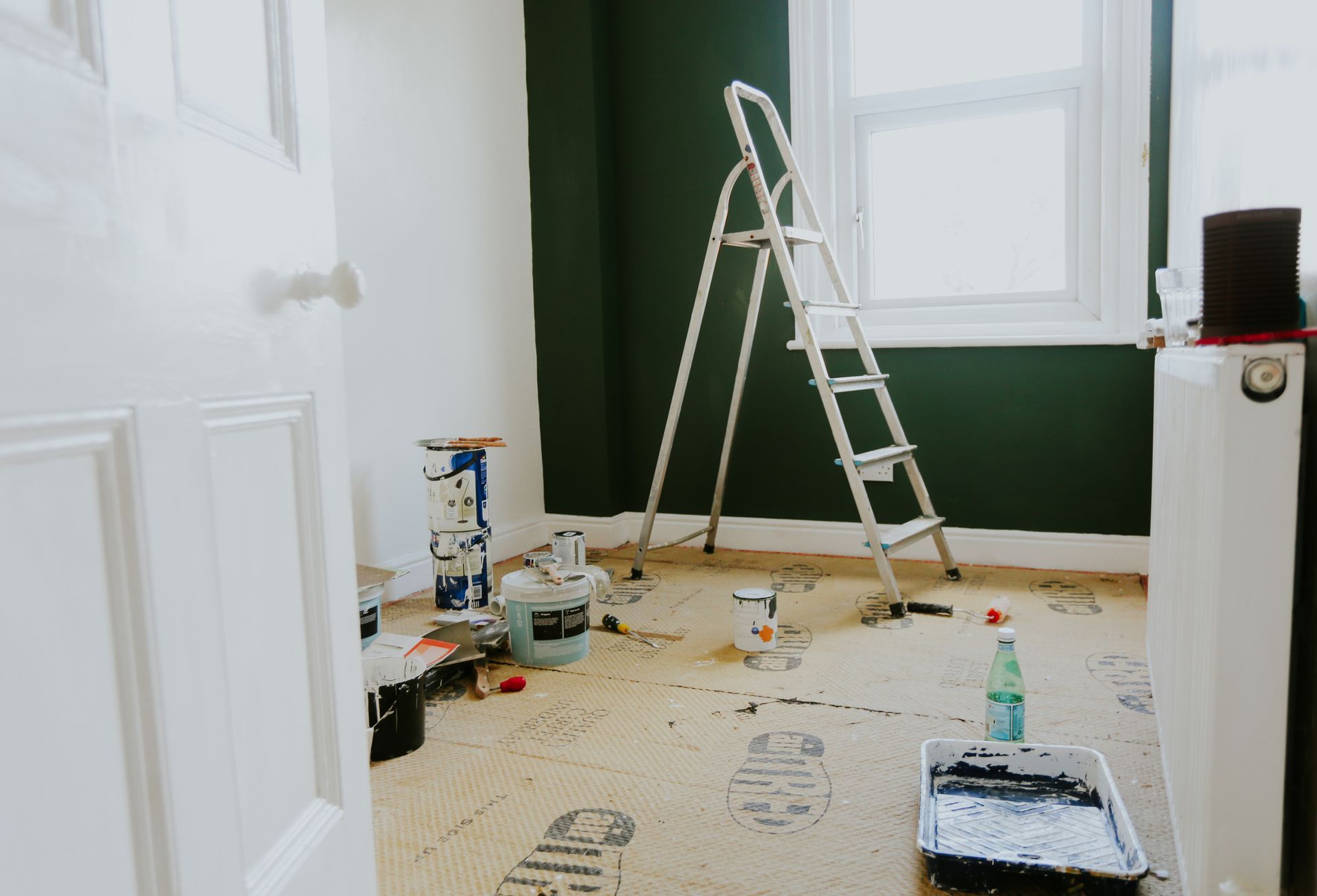 A room is being painted with green walls and a ladder.
