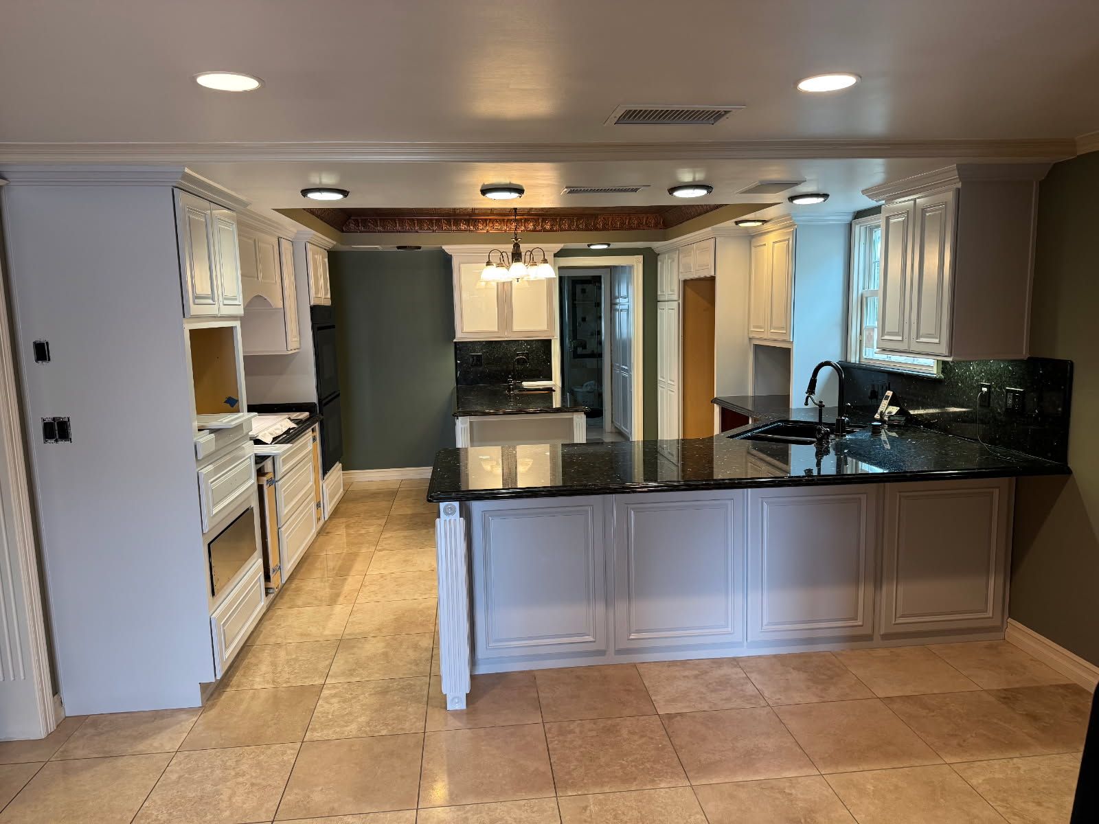 A kitchen with white cabinets and a black counter top.