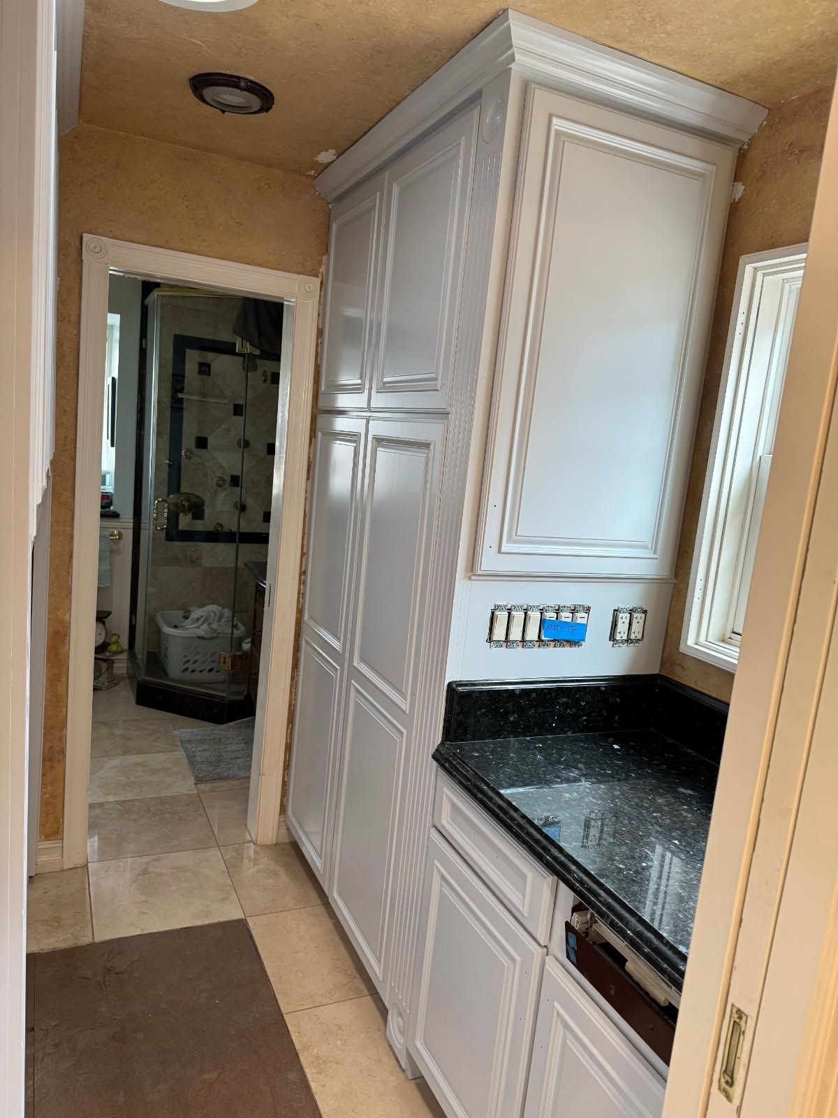 A kitchen with white cabinets and black counter tops