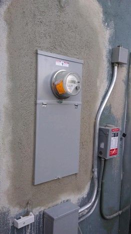 A electrical box is attached to the side of a building.
