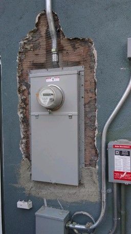 A meter is sitting in a hole in a wall.