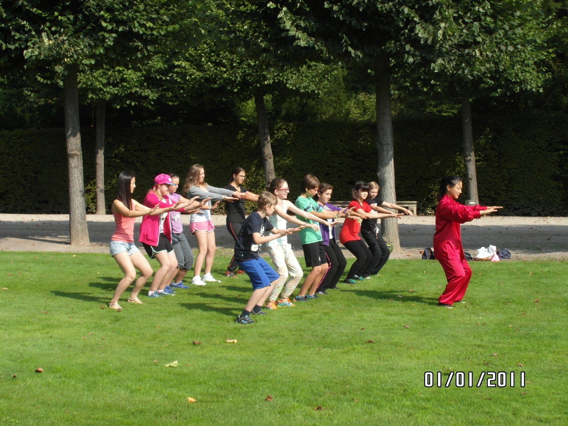 Eine Gruppe von Menschen praktiziert an einem sonnigen Tag in einem Park Kampfsport